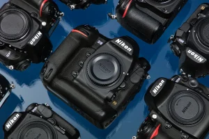 High-angle shot of various Nikon DSLR and mirrorless cameras and lenses spread across a textured surface.
